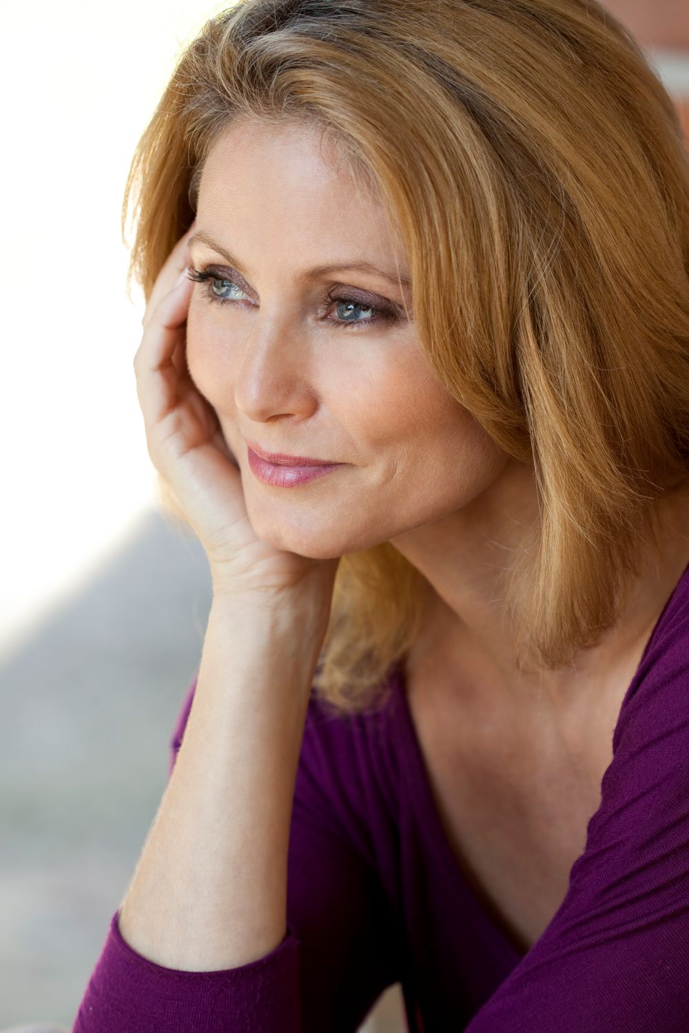 Smiling woman with yellow eye makeup and sunlight.