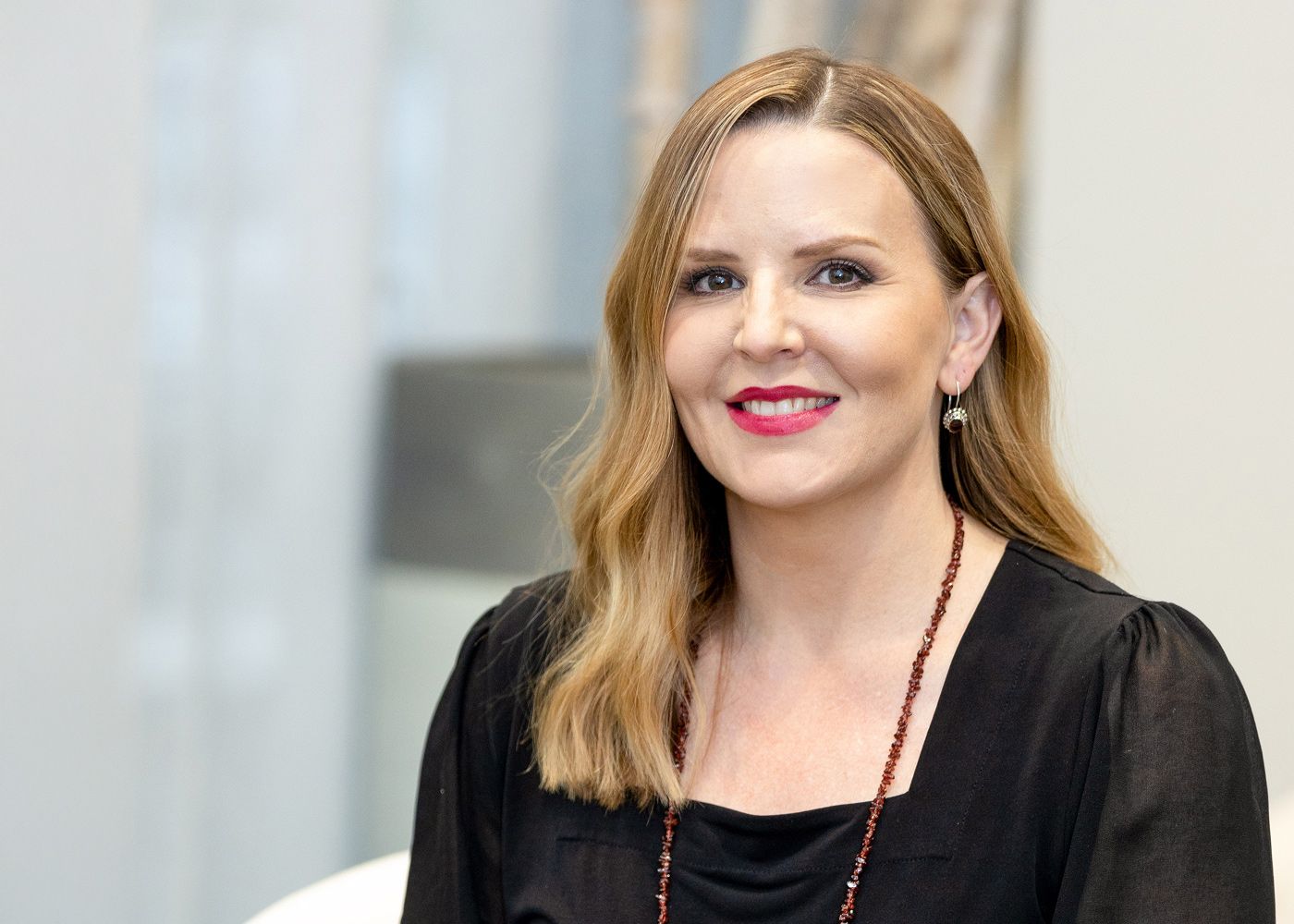 Smiling woman with long hair and earrings.