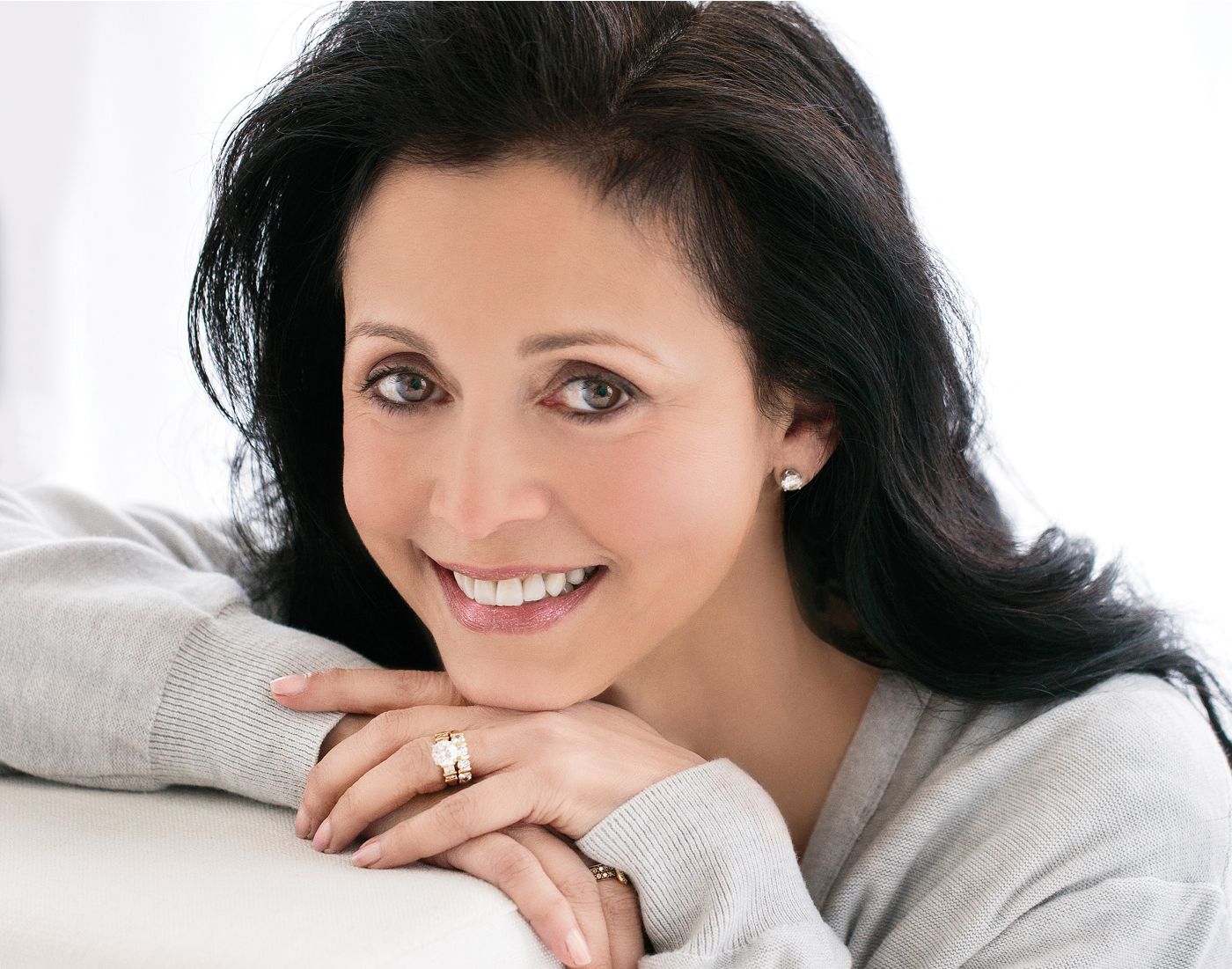 Smiling woman resting her chin on hands.