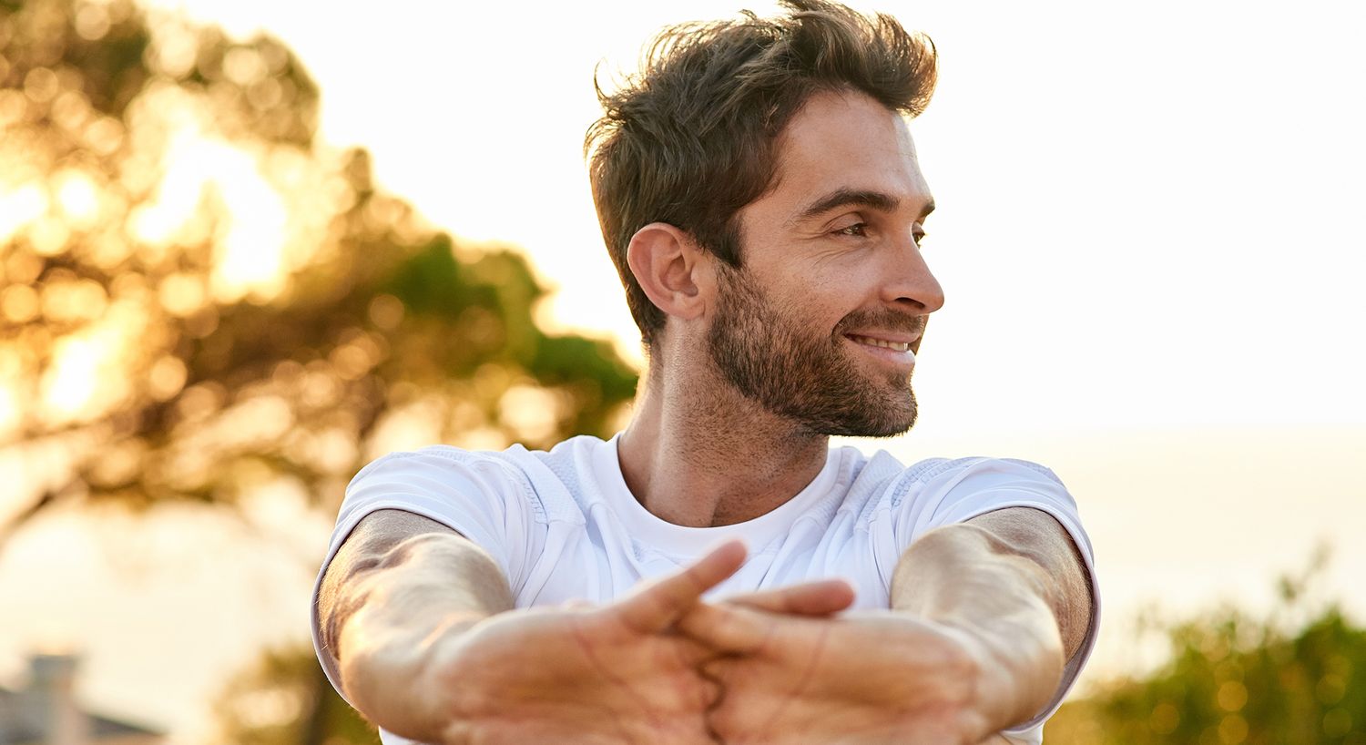 Man stretching outdoors during sunset.