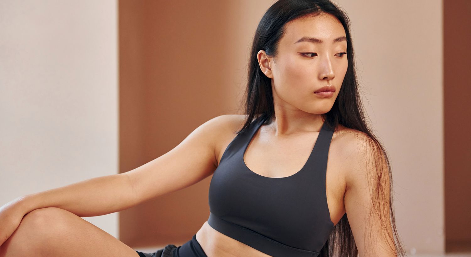 Woman in athletic wear looking thoughtfully to side.