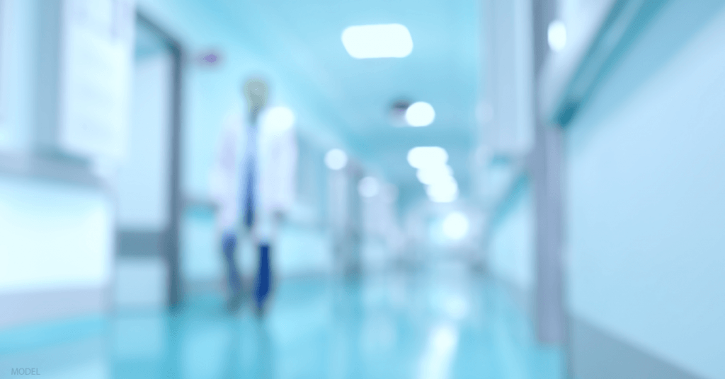An out of focus image of a doctor walking down a hallway.